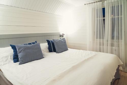een wit bed met blauwe kussens en een raam bij Salt & Sill in Klädesholmen