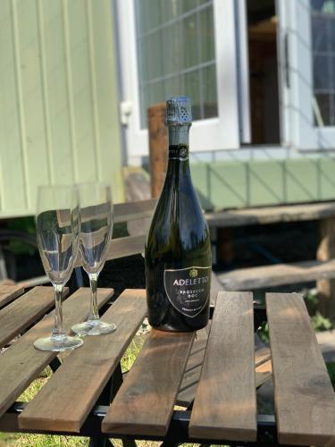 a bottle of wine sitting on a picnic table with two glasses at Hillcrest Hut in Tenby