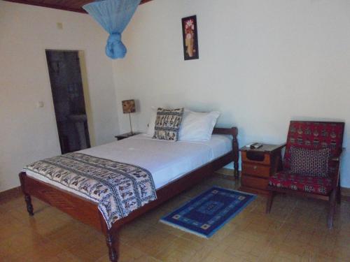 ein Schlafzimmer mit einem Bett und einem Stuhl darin in der Unterkunft Residencialdes in São Tomé