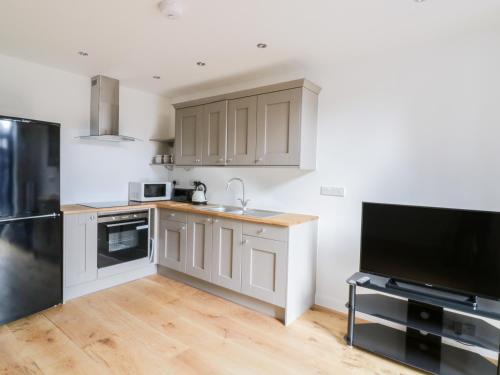 a kitchen with white cabinets and a flat screen tv at Grange Barn in Hessett