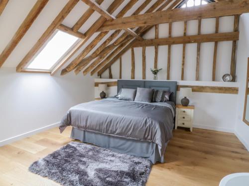 een slaapkamer met een groot bed op zolder bij Grange Barn in Hessett