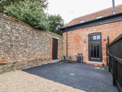 a brick building with a table next to a door at Grange Barn in Hessett