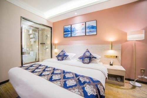 a hotel room with a large bed and a bathroom at Demei Boutique Hotel in Kunming