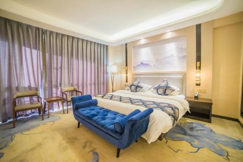 a hotel room with a large bed and a blue couch at Demei Boutique Hotel in Kunming
