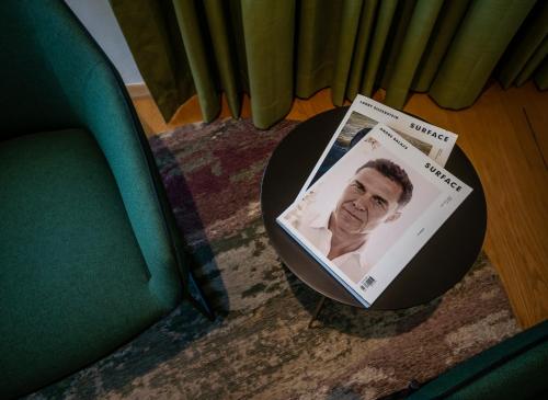 a magazine sitting on a table next to a chair at Schumacher Hotel Haifa in Haifa