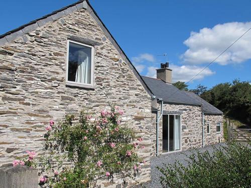 a stone house with a window and flowers in front of it at Cefn Isaf in Porthmadog