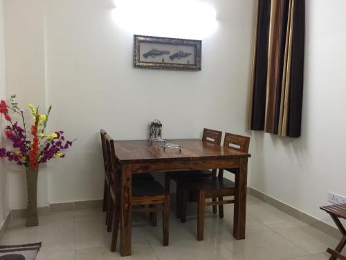 a dining room table with chairs and a vase with flowers at The Raveesh E24 - 2BHK Serviced Apartment in New Delhi