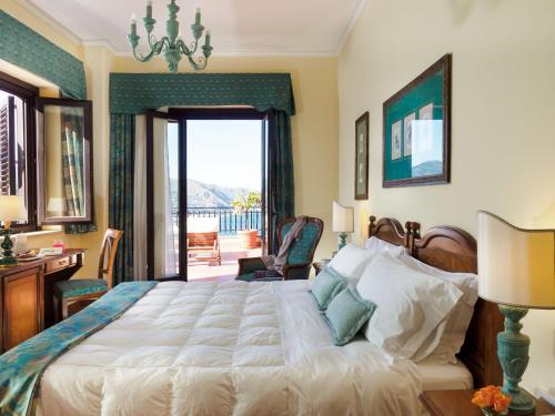 a bedroom with a large bed and a balcony at Hotel Sirius in Taormina