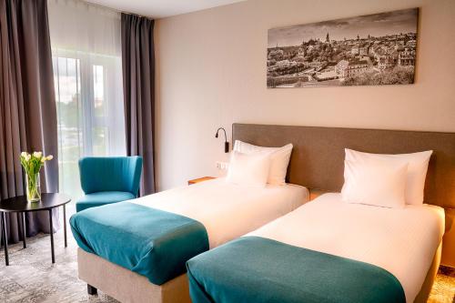 a hotel room with two beds and a chair at Focus Hotel Premium Lublin in Lublin