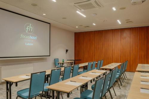 a conference room with tables and chairs and a screen at Focus Hotel Premium Lublin in Lublin