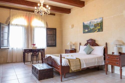 a bedroom with a bed and a table and a window at Villayana Holiday Home in San Lawrenz