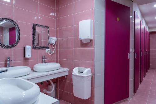 a pink bathroom with two sinks and a mirror at Hostel Inbox in Skopje