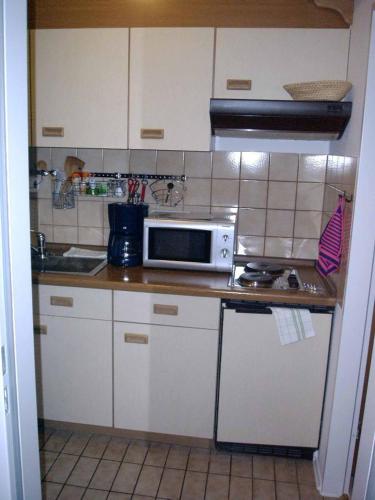 a kitchen with white cabinets and a microwave on a counter at Appartementhaus Margarita in Bad Füssing