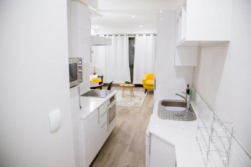 a white kitchen with a sink and a living room at Apartment 617 The Regency in Pretoria