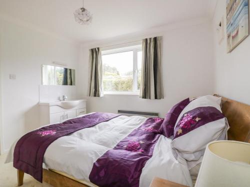 a bedroom with a bed with a purple blanket at Brambles in Gorran Haven