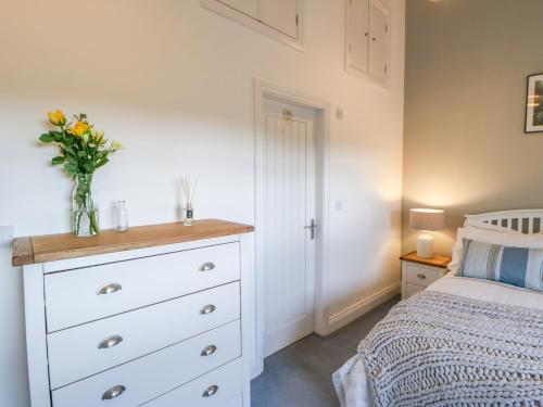 a bedroom with a white dresser with a vase of flowers on it at The Byre in Stockton-on-Tees