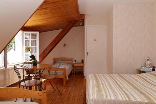 1 dormitorio con mesa, cama, mesa y sillas en Chambres d'hotes à Autun, en Autun