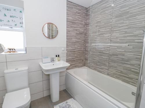 a bathroom with a tub and a sink and a toilet at Hafan Traeth Beach Haven in Benllech