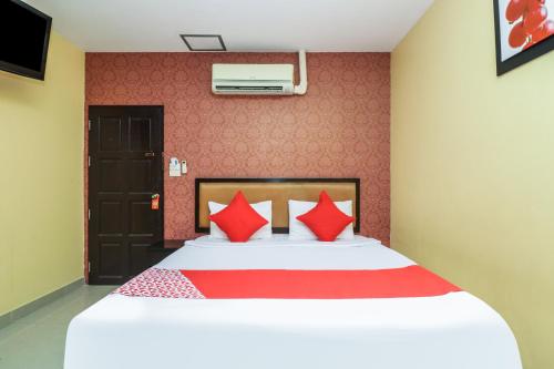 OYO 131 Griebs Inn في جنوب باتايا: غرفة نوم بسرير كبير ومخدات حمراء