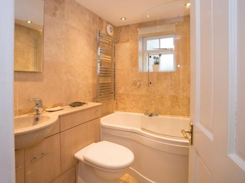 a bathroom with a toilet and a tub and a sink at The Coach House - Beaumaris in Beaumaris
