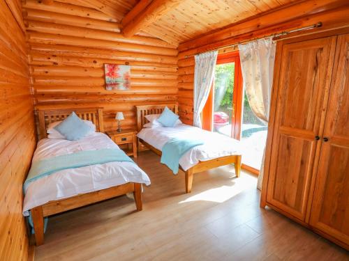 a bedroom with two beds in a log cabin at Yew Lodge in Oakham