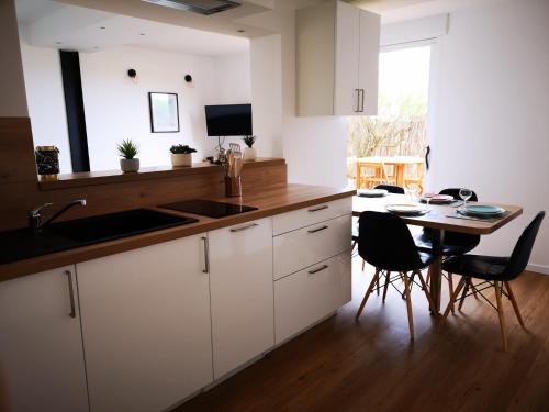 a kitchen with white cabinets and a table with chairs at L'horizon - Bord de mer in Ploemeur