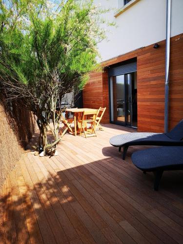 une terrasse en bois avec une table et un arbre dans l'établissement L'horizon - Bord de mer, à Ploemeur