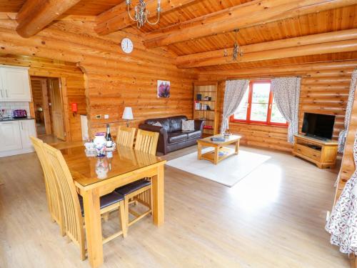 a dining room and living room in a log cabin at Beech Lodge in Oakham