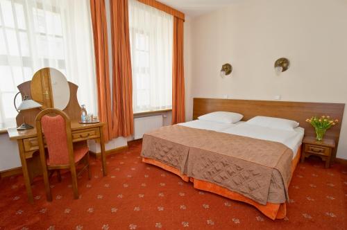 a bedroom with a bed and a desk and a mirror at Hotel Regent in Kraków