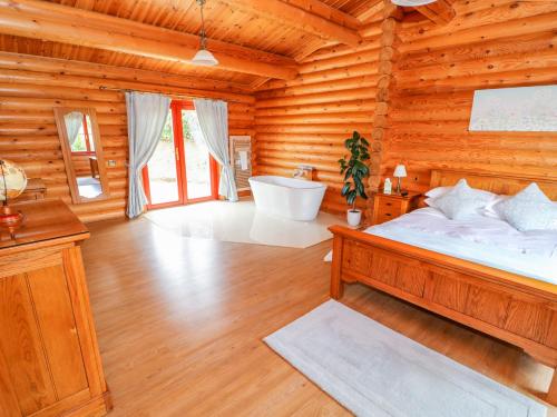 a bedroom with a bed and a tub in a log cabin at Cedar Lodge in Oakham