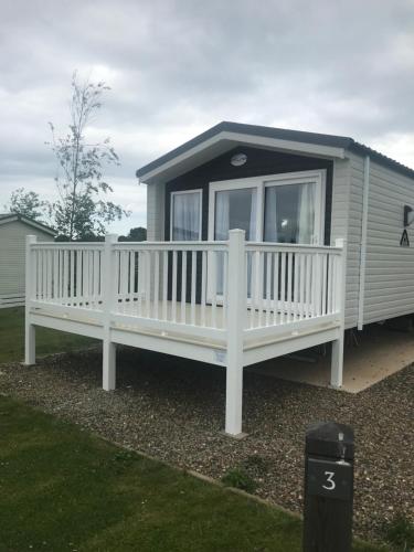 a mobile home with a large porch and a white deck at Modern mobile home premium pitch in Port Seton