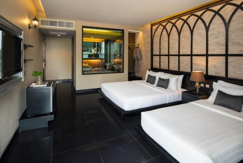 a hotel room with two beds and a television at TSix5 Quarter in Pattaya North