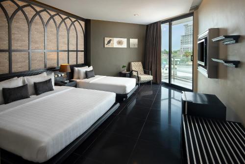 a hotel room with two beds and a balcony at TSix5 Quarter in Pattaya North