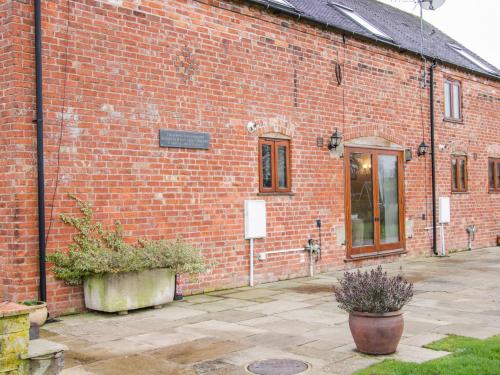 a red brick building with a door and some plants at Southdown in Much Wenlock