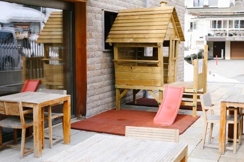 a wooden dog house on a patio with tables and chairs at Nira Alpina in Silvaplana