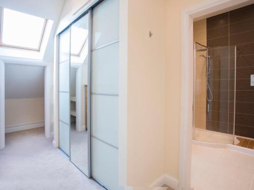 a glass pivot door in a bathroom with a shower at Dol Fraint in Llanfairpwllgwyngyll