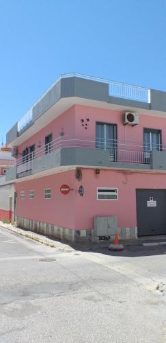 a pink building with a balcony on the side of it at Time Holiday´s House in Olhão