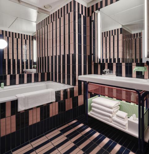 a bathroom with a tub and a sink and towels at The Standard London in London