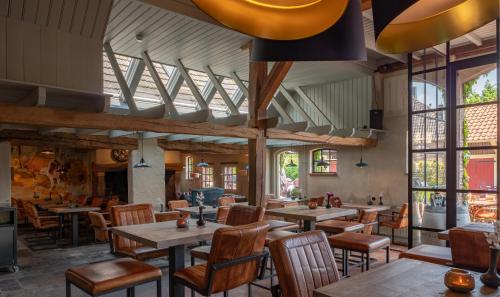 a restaurant with tables and chairs and windows at Herberg de Gouden Leeuw in Bronkhorst