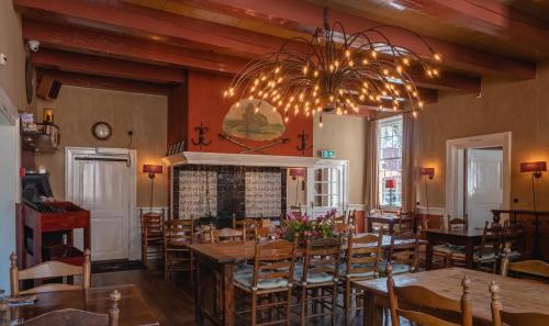 a dining room with tables and chairs and a chandelier at Herberg de Gouden Leeuw in Bronkhorst