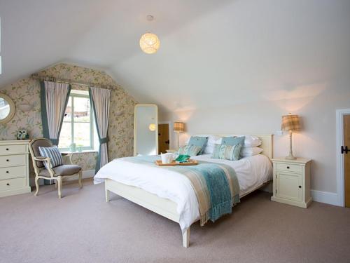 a bedroom with a large bed and a chair at Estuary Cottage in Penrhos-Lligwy