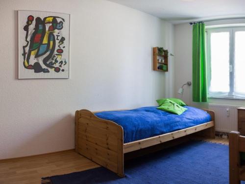 ランゲナルゲンにあるFerienwohnung Ernst-Stroblのベッドルーム1室(青いシーツと緑のカーテンが備わるベッド1台付)