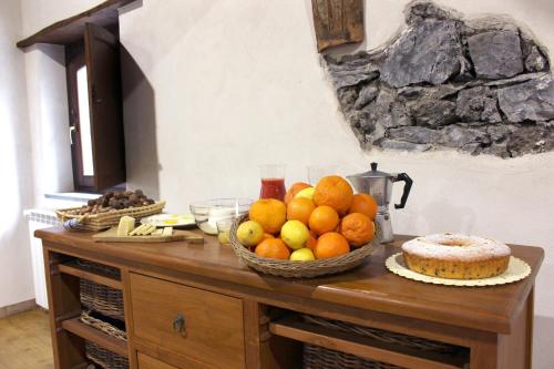 a table with a bowl of fruit and a cake at Agriturismo La Caraffara sull' Etna in Puntalazzo