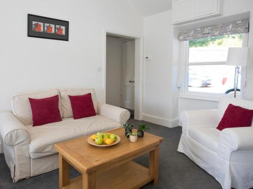 a living room with a couch and a table with a bowl of fruit at Glan Dwr Bach in Llandegfan