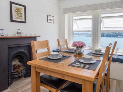 a dining room with a table and a fireplace at Glan Dwr Bach in Llandegfan