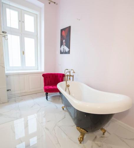 a bathroom with a tub and a red chair at Rooms in a luxury gorgeous newly refurbished apartment - historic centre in Bratislava