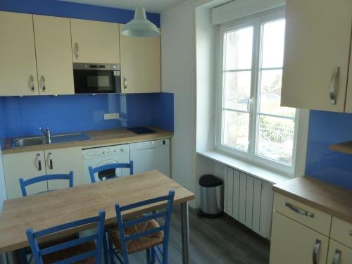 - une cuisine avec une table en bois et des murs bleus dans l'établissement Le Petit Bleu - Appt à 5m de la plage, à Dinard