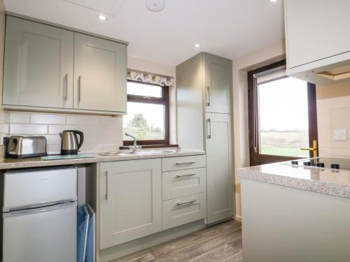 a kitchen with white cabinets and a window at Little May in Newquay