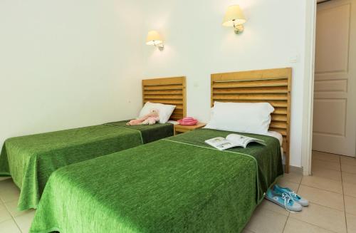 - 2 lits dans une chambre avec des draps verts dans l'établissement Résidence Odalys Acqua Bella, à Poggio-Mezzana