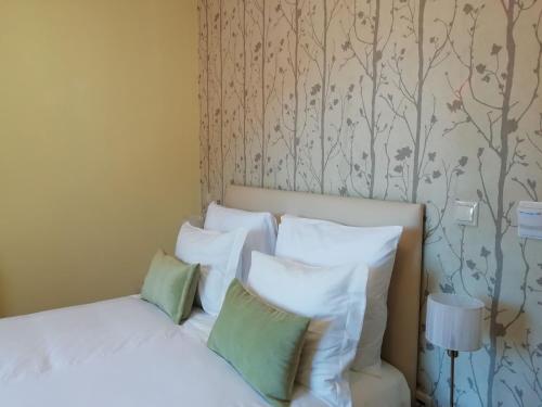 a bedroom with a bed with white sheets and green pillows at Adelaide Hotel in Geres